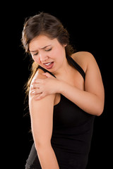 Fototapeta premium Beautiful young woman suffer from shoulder pain in a black background