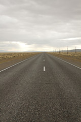 A long straight road leading to a mountain in Altai, Russia. Beautiful steppe view on a cloudy day
