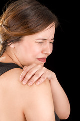 Close up of a beautiful young woman suffer from shoulder pain in a black background