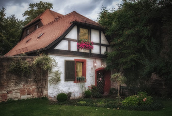 Fototapeta na wymiar Kleines Haus mit Bank und Blumen