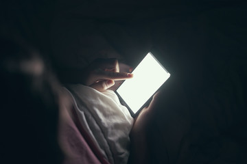 Close-up. The smartphone is held in hands. With one hand, point to the display. Lying in bed....