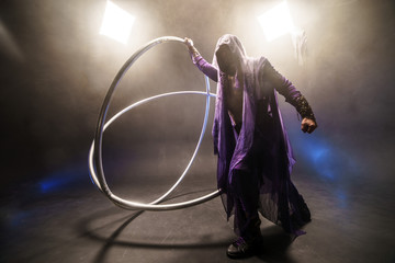 Fairy-tale character assassin in a purple cloak with a hood with two large cross wheel