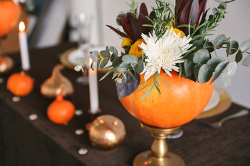 autumn floral bouquet in a pumpkin vase for Halloween. Table setting for wedding