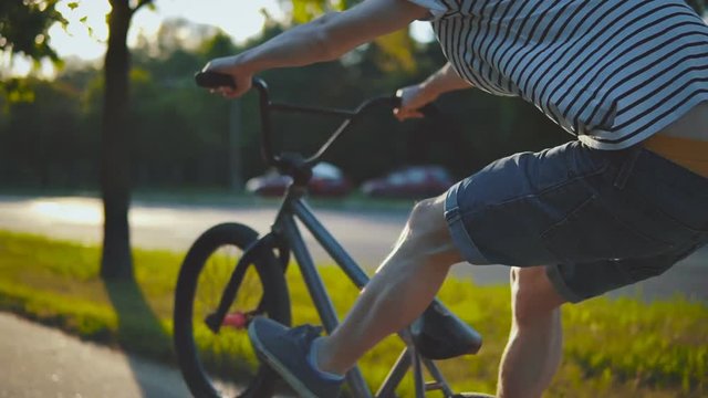 SLOW MO: bmx biker riding on back wheel on sunny day doing wheelie trick