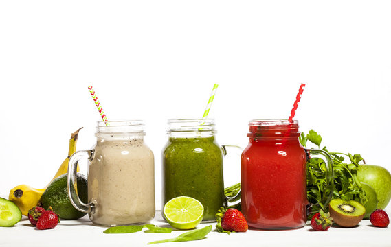 Assortment of fruit and vegetable smoothies in glass jars with straws