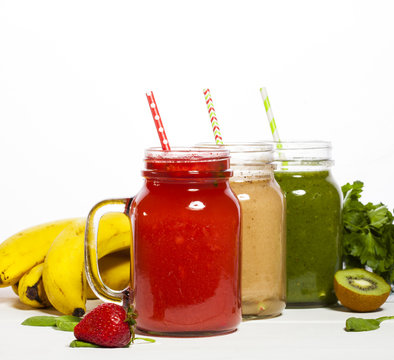 Assortment of fruit and vegetable smoothies in glass jars with straws