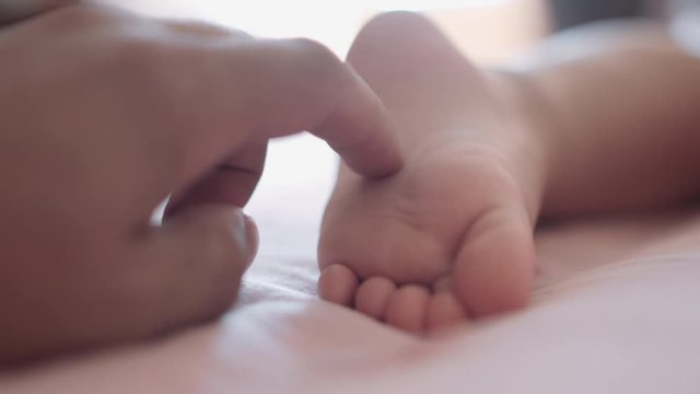 Hand stroking the leg of a sleeping child. The tickling. Close-up.