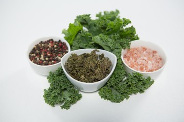 High angle view of salt and peppercorns with kale