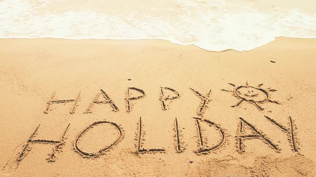	Happy Holiday! Written in sand at the beach. Holiday concept.