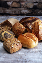 Different kinds of bread and bread rolls on board. Kitchen or ba