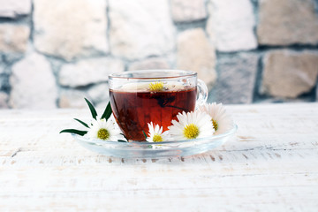 cup of tea with chamomile flowers on rustic background
