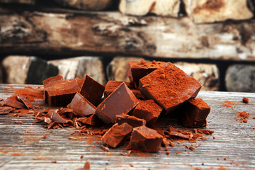 Chocolate cream melted, chocolate pieces and chocolate powder on wooden table