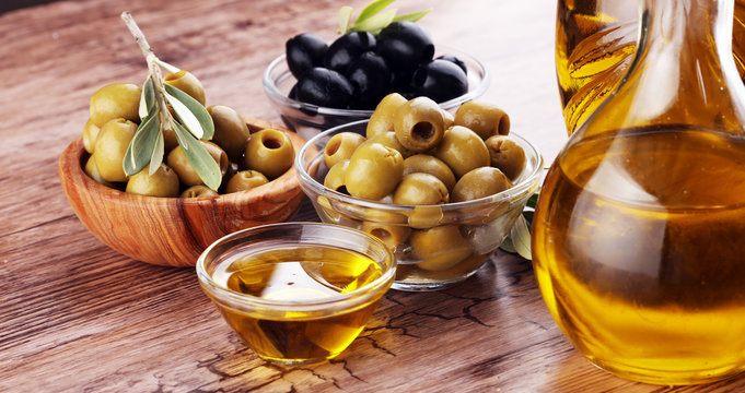 Bottle virgin olive oil and oil in a bowl with some olives