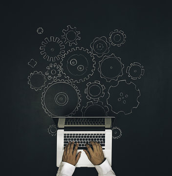 Man working . Draw of gears mechanism on chalkboard.