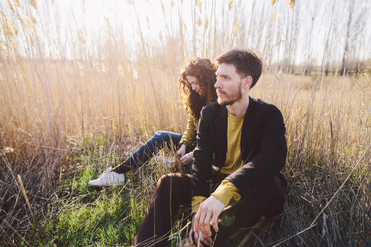 Young couple sitting among tall dry grass