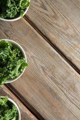 Overhead view of kale in bowls on brown table
