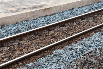 Railroad tracks with rocks near the concrete.