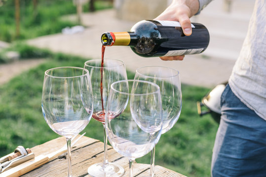 Young man pouring red wine into glasses
