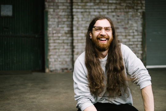 Man sitting on a loading dock with a brick wall behind him