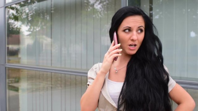 An attractive black-haired woman is talking on the phone