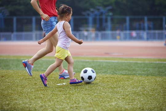 Little girl playing football outdoor in the football field