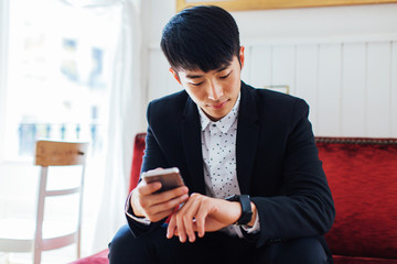 Portrait of a young businessman watching his smart watch sitting in a coffee bar.