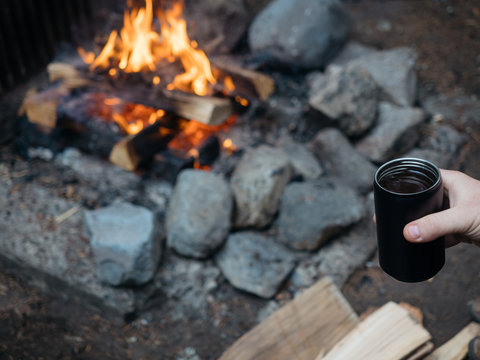 Coffee in mug held near campfire in National Park, Washington.