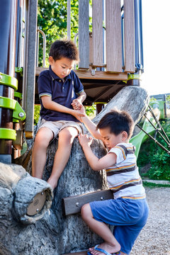 Asian Kids Helping Each Other In The Playground