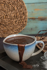 Delicious melted chocolate sauce in mug with whisk on table