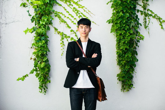 Portrait of an asian businessman standing in front of an ivy wall