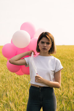 Serious teen girl with balloons looking at camera