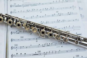 Obraz premium Silver French flute laying diagonally across sheet music