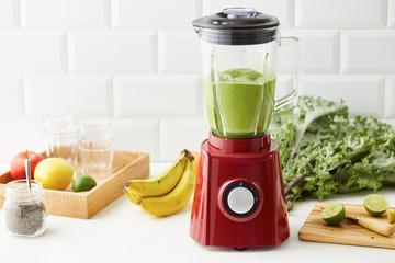 Green smoothie drink in blender on kitchen table