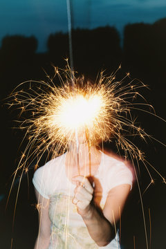 young blonde girl holding a burning sparkler