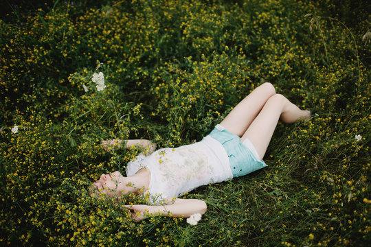Carefree blonde girl lie down in a yellow flowers