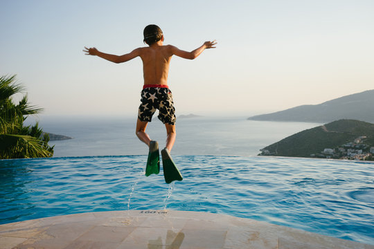 Boy jumping into pool in silly way
