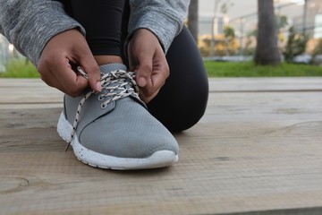 Low section of female athlete tying shoelace - Powered by Adobe