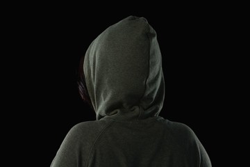 Naklejka na ściany i meble Female athlete in hooded jacket against black background