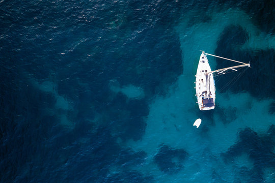 Fototapeta Aerial view of anchored sailing yacht in emerald sea