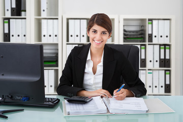 Obraz na płótnie Canvas Confident Businesswoman Using Calculator At Office Desk