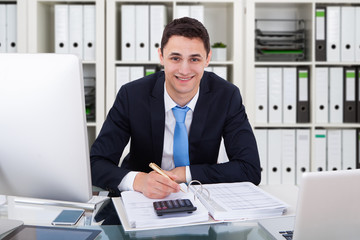 Smiling Businessman Calculating Tax