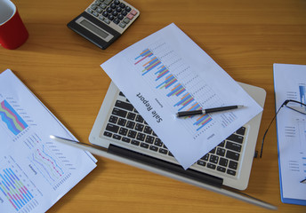 Obraz premium Laptop with financial documents on wooden table
