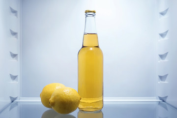 Bottle of lemonade with fresh lemons in fridge