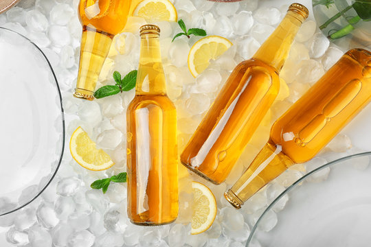 Bottles of lemonade on ice background
