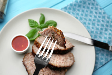 Fork with slice of tasty turkey meatloaf over table