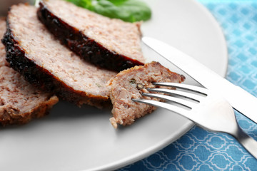 Fork with slice of tasty turkey meatloaf on plate, closeup
