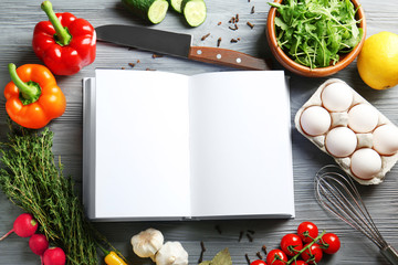 Open notebook and vegetables on kitchen table. Cooking classes concept