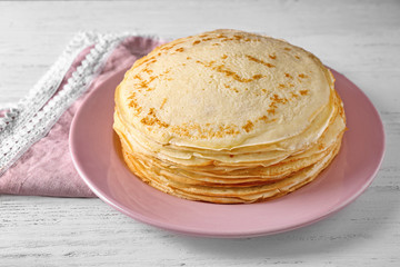 Stack of delicious thin pancakes on pink plate