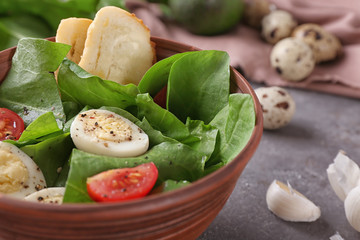 Salad with quail eggs and spinach in bowl on table