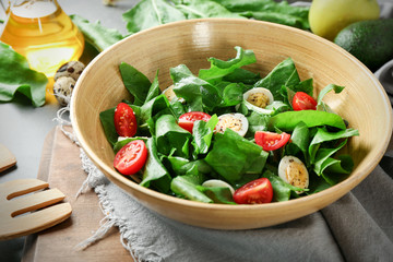 Salad with quail eggs and spinach in bowl on table